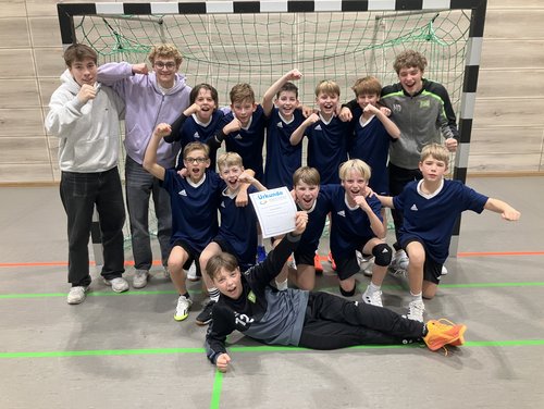 Handball-Mannschaft zeigt vor dem Tor die Siegerurkunde