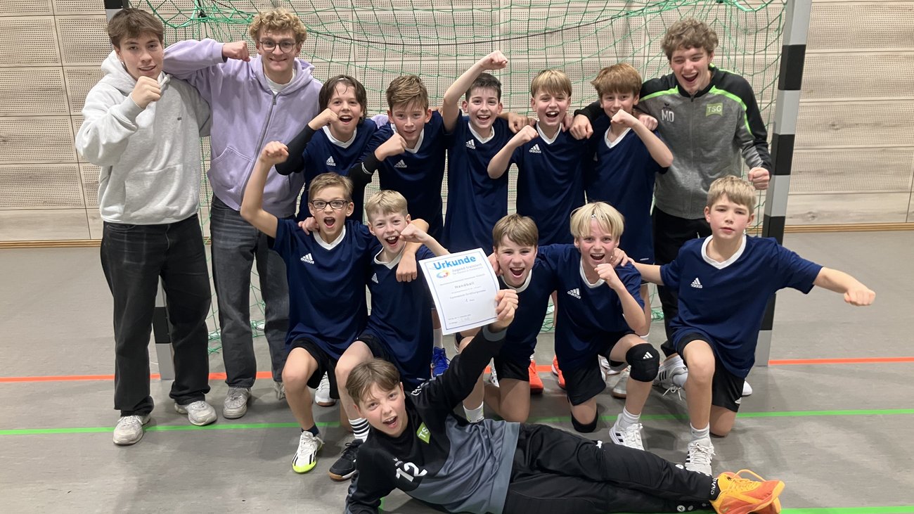 Handball-Mannschaft zeigt vor dem Tor die Siegerurkunde