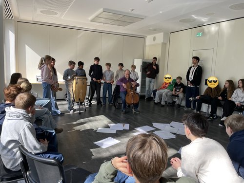 Ein Musiker stellt spielt Cello vor Schülern.