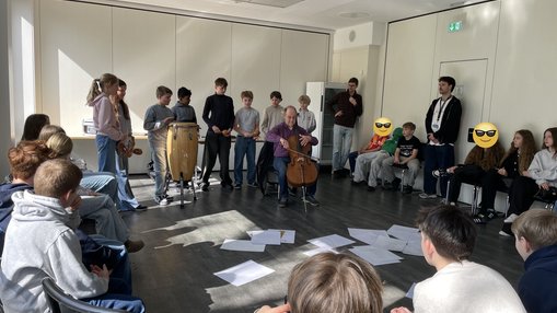 Ein Musiker stellt spielt Cello vor Schülern.