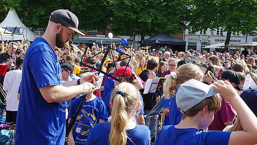 Ein Lehrer baut Schülerinnen und Schülern einen Notenständer auf.